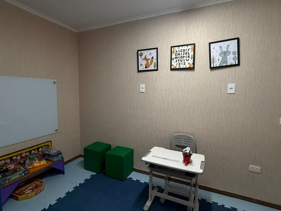 Sala de atendimento infantil com brinquedos e lousa