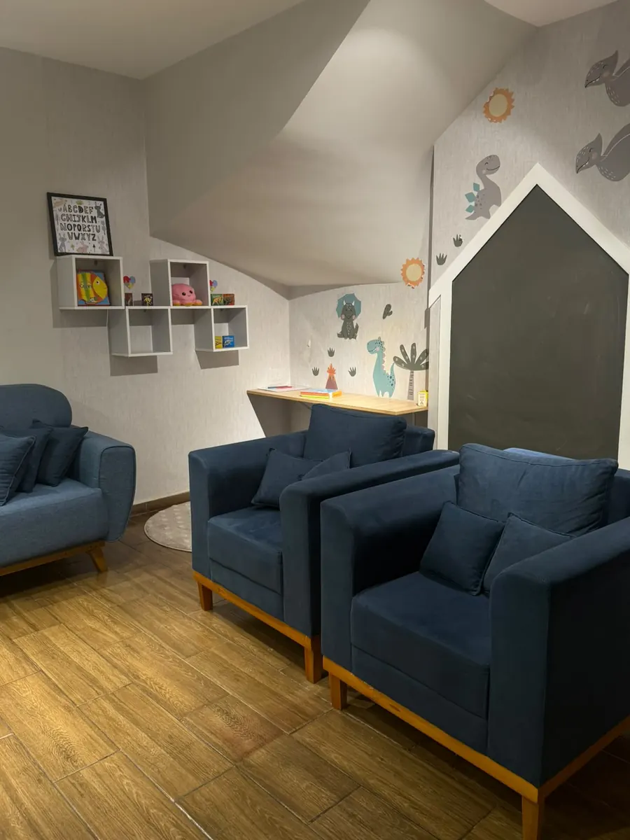 Sala lúdica com poltronas azuis e decoração de dinossauros